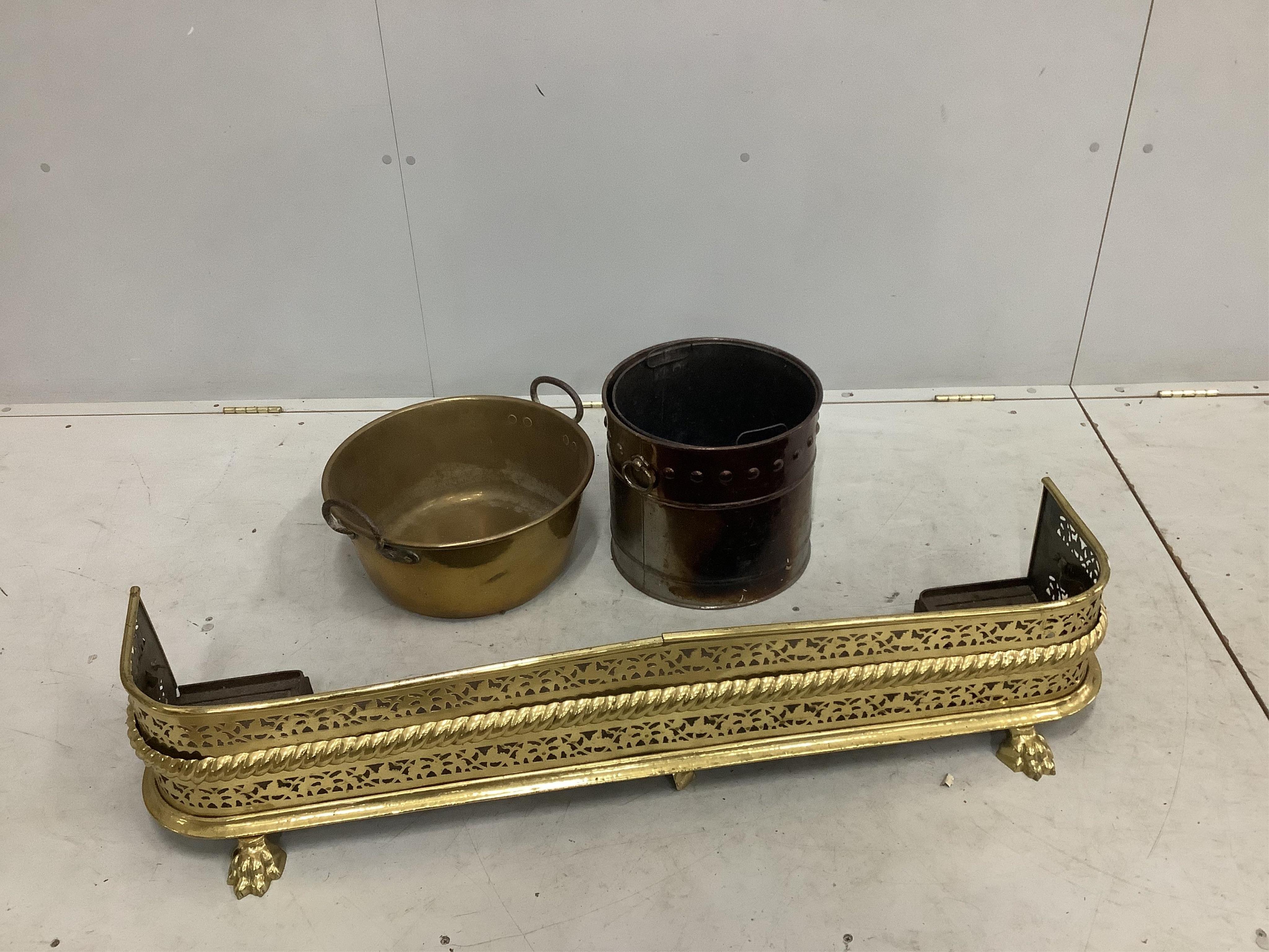 A 19th century brass fender on lion's paw feet, width 120cm, together with a steel coal bucket and a brass preserving pan. Condition - fair